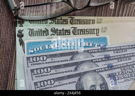 Gefälschte Sozialversicherungskarte auf US-Währung und Schecks des Finanzministeriums Stockfoto