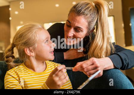 Fröhliche Mutter und Tochter, die miteinander interagieren und Ohrringe in einem Einkaufszentrum anschauen Stockfoto