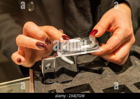 Hand bereitet eine Ohrpiercpistole in einem Juweliergeschäft vor, bereitet sich auf ein Ohrläppchen vor Stockfoto