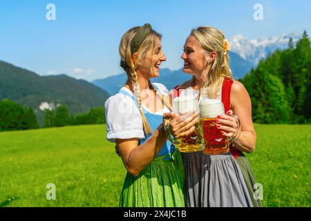 Zwei glückliche Frau mit schaumigen Bierkrügen in Tracht, Dirndl in den Bayerischen alpen oder oktoberfest Stockfoto