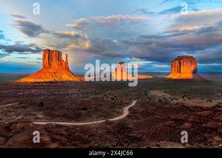 Dramatischer Blick auf den herrlichen butte und die Fäustlinge des Monument Valley, die bei Sonnenuntergang beleuchtet und von bunten Wolken eines vorbeiziehenden Sturms eingerahmt werden. Stockfoto