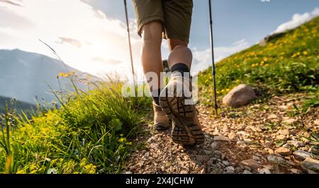 Nahaufnahme von Wanderweibchen, die auf einem Bergweg mit Trekkingstöcken und Wildblumenberglandschaft in den deutschen alpen wandern Stockfoto