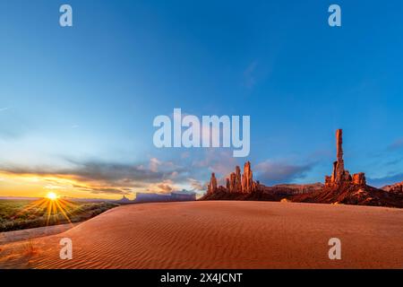 Die von der aufgehenden Sonne beleuchtete Berglandschaft wirft eine orange Farbe auf die Landschaft im Monument Valley, Arizona, ein Reiseziel für Abenteuer im Südwesten Stockfoto