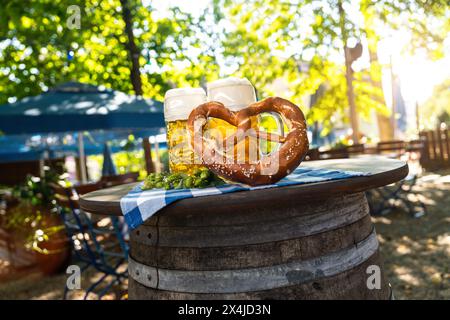 Bierbecher mit frischer Brezel oder Brezen auf dem Oktoberfest oder Biergarten im Sommer in München Stockfoto