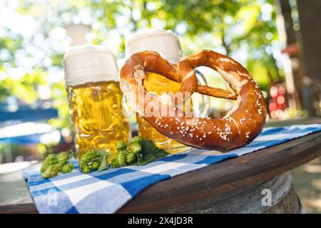 Bierbecher mit frischer Brezel oder Brezen auf dem Oktoberfest oder Biergarten im Sommer in München Stockfoto