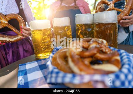 Freunde mit einem frischen Bier in einem Biergarten, Nahaufnahme mit Bier stein und Brezeln Stockfoto