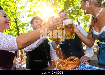 Eine Gruppe glücklicher bayerischer Freunde, die Bier trinken und anstoßen beim Oktoberfest, Folk- oder Bierfestival in deutschland Stockfoto