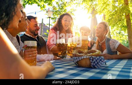 Kellnerin holt Bier in Bechern an die Gäste eines Biergardens oder oktoberfestes in Bayern im Sommer Stockfoto