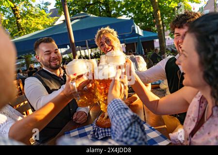 Gruppe fröhlicher Menschen, die Bier trinken und beim Biergarten oder oktoberfest in Bayern in die Kamera schauen, Stockfoto