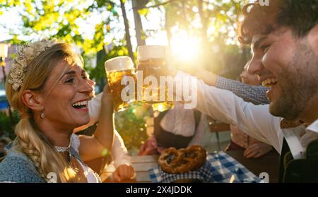 Gruppe von Freunden im Biergarten, die im Sommer mit Bierbecher toasten Stockfoto