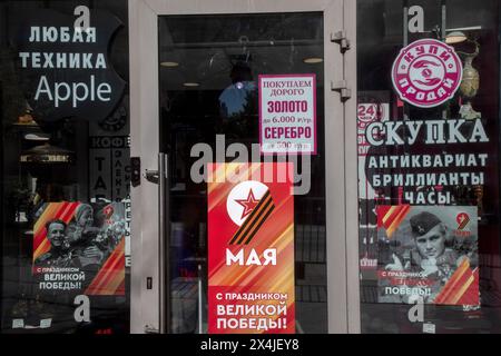 Moskau, Russland. Mai 2024. Glastüren zu einem Pfandhaus sind festlich dekoriert, um den Tag des Sieges am 9. Mai in der Twerskaja Straße im Zentrum von Moskau, Russland, zu feiern Stockfoto