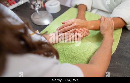 Frau, die eine Massage in einem Schönheitssalon mit einem Maniküre erhält, der an ihren Nägeln arbeitet Stockfoto