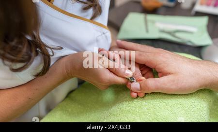 Maniküre mit Nagelzangen an den Nägeln eines männlichen Klienten während einer Maniküre Stockfoto