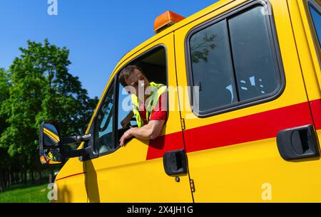 Fahrer eines Abschleppwagens, der in einem gelben Lkw sitzt und aus dem Fenster blickt und prüft, ob er manövrieren kann Stockfoto