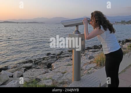 Die Frau blickt durch ein Fernglas auf das Meerespanorama. Stockfoto