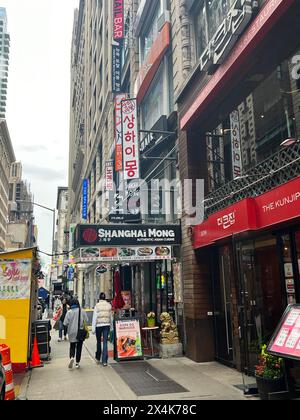 Gehen Sie den Bürgersteig in Koreatown entlang, West 32nd Street in Manhattan zwischen 5th und 6th Avenue. Stockfoto