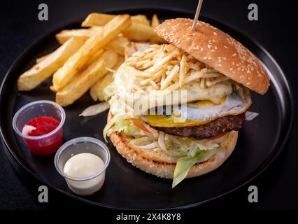 Käse Burguer Sandwich mit Pommes Frites auf Papier mit schwarzem Hintergrund Stockfoto