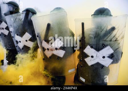 Die Polizei bildet eine Schnur mit Perspex-Schilden und trägt Helme - gelber Rauch Stockfoto