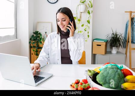 Junge lächelnde Ernährungsberaterin im Sprechzimmer Stockfoto