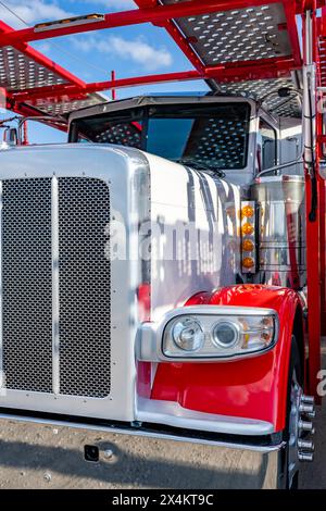 Industrietauglicher weißer und roter Kfz-Transportwagen großer Lkw mit verlängerter Fahrerkabine für LKW-Fahrer-Ruhestellung und leerer Auflieger auf dem Geschäft Stockfoto