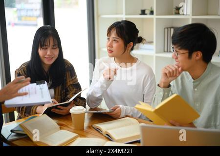 Gruppe von Studenten, die an einem Tisch in der Bibliothek sitzen und über Forschung diskutieren Stockfoto