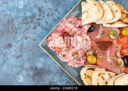 Catering-Box mit Salami, Schinken und Brotstangen, Aufschnitt, Fleischscheiben und Salz mit Croutons und Brotstäbchen auf dem Teller. Kopierbereich Stockfoto