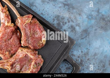 Auf dem Knochen mariniertes Lammgestell liegt auf einer schwarzen Steinplatte. Draufsicht, Kopierraum Stockfoto