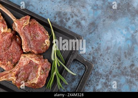 Auf dem Knochen mariniertes Lammgestell liegt auf einer schwarzen Steinplatte. Draufsicht, Kopierraum Stockfoto