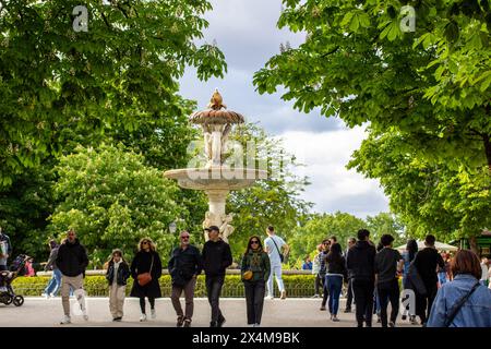 Madrid, Spanien. 2. Mai 2024 Eine Menschenmenge, die in einem botanischen Garten auf einer Straße der Stadt spaziert. Zeit im Freien verbringen. Antike Brunnen Wahrzeichen. Stockfoto