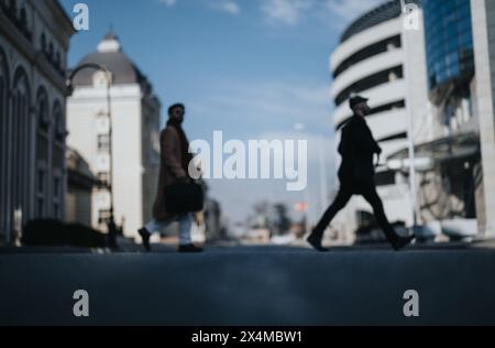 Verschwommene Silhouette von zwei Geschäftsleuten, die in urbaner Umgebung spazieren gehen. Stockfoto