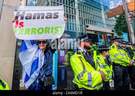 London, Großbritannien. Mai 2024. Eine kleine Gruppe von Pro-Israel-Demonstranten versucht, sich unter die Menge zu mischen (mit Pl;acards, die sagen, Hamas seien Terroristen, genug ist genug anbd Hamas=Isis), sie werden von der Polizei gebeten, die palästinensischen Demonstranten nicht zu konfrontieren - Ein palästinensischer Protest, Aufruf zu einem Waffenstillstand und Beendigung der Bewaffnung von Israel Palästina Protest an der Barclays Bank Tottenham Court Road. Die Demonstranten sagen, Barcalys sei "einer der größten Geldgeber des Waffenhandels mit Israel". Guy Bell/Alamy Live News Stockfoto