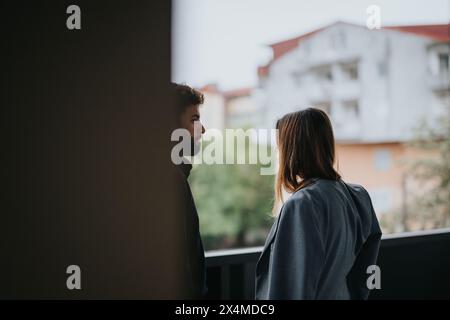 Zwei junge Berufstätige, die sich auf einem Balkon mit Blick auf die Stadt unterhalten Stockfoto