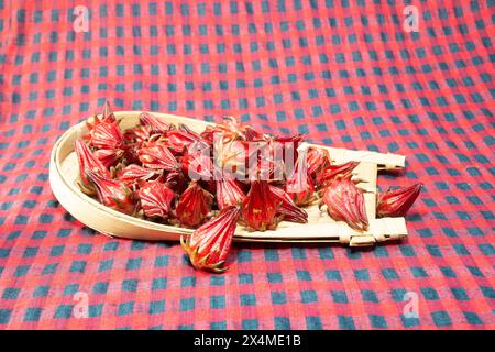 Roselblume ist ein Kraut mit saurem Geschmack und wird häufig zur Tee-Zubereitung verwendet. Hibiscus sabdariffa. Auf einem Bambustablett. Stockfoto