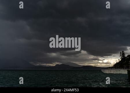 Panorama des Lago Maggiore an einem regnerischen Tag mit schweren niedrigen Wolken, die einen Teil der Küste bedecken - Reise- und Urlaubskonzept Stockfoto