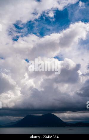 Panorama des Lago Maggiore an einem regnerischen Tag mit schweren niedrigen Wolken, die einen Teil der Küste bedecken - Reise- und Urlaubskonzept Stockfoto