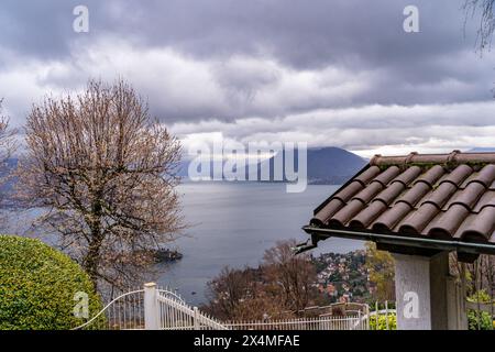 Panorama des Lago Maggiore an einem regnerischen Tag mit schweren niedrigen Wolken, die einen Teil der Küste bedecken - Reise- und Urlaubskonzept Stockfoto