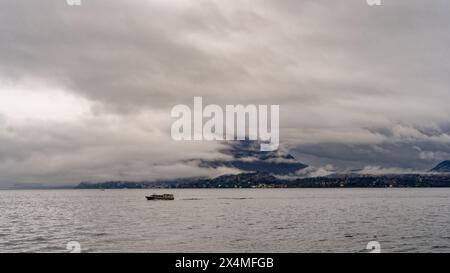 Panorama des Lago Maggiore an einem regnerischen Tag mit schweren niedrigen Wolken, die einen Teil der Küste bedecken - Reise- und Urlaubskonzept Stockfoto