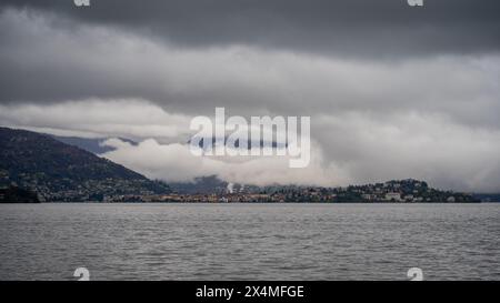 Panorama des Lago Maggiore an einem regnerischen Tag mit schweren niedrigen Wolken, die einen Teil der Küste bedecken - Reise- und Urlaubskonzept Stockfoto