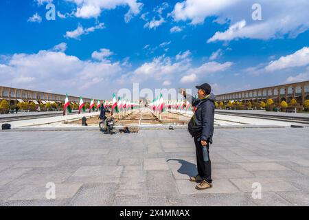 Naqsh Jahan Square, Iran - 5. März 2024: Touristen haben einen atemberaubenden Blick auf die historische Stätte, die mit Flaggenreihen unter einem klaren blauen Himmel geschmückt ist, aufgenommen. Stockfoto