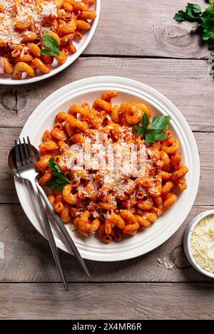 Pasta Cavatappi mit Tomatensauce und geriebenem Parmesankäse auf hölzernem Hintergrund, Blick von oben. Hausgemachte vegetarische Pasta mit Parmesan. Stockfoto