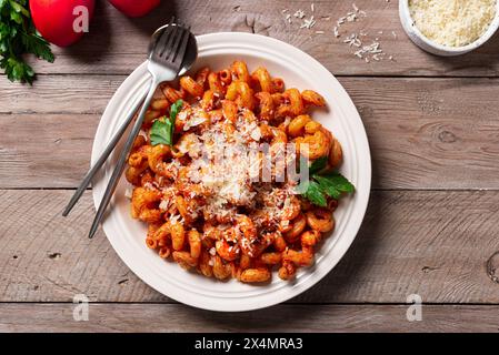 Cavatappi Pasta mit Tomatensauce und geriebenem Parmesankäse auf Holztisch, Blick von oben. Hausgemachte vegetarische Nudeln mit reichhaltiger roter Sauce. Stockfoto