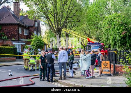 London, Großbritannien. Mai 2024. Viele Feuerwehrfahrzeuge, Krankenwagen und Polizisten nehmen bei einem Brand in einem großen Haus an der Elsworthy Road im Gebiet von Primrose Hill Teil. Das Feuer scheint klein gewesen zu sein und ist aus und die Notfallteams beginnen sich zu zerstreuen, während die vertriebene Familie zusieht. Zehn Feuerwehrfahrzeuge und etwa 70 Feuerwehrleute reagierten. Die Hälfte des zweiten Obergeschosses in einem freistehenden Haus mit drei Stockwerken wurde durch den Brand beschädigt. Eine der 32 m hohen Leiter der Brigade wurde zusammen mit Feuerwehrleuten aus West Hampstead, Paddington, Kentish Town eingesetzt. Credit Guy Bell/Alamy Live News Stockfoto