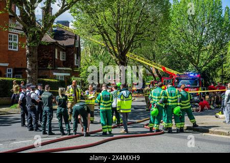 London, Großbritannien. Mai 2024. Viele Feuerwehrfahrzeuge, Krankenwagen und Polizisten nehmen bei einem Brand in einem großen Haus an der Elsworthy Road im Gebiet von Primrose Hill Teil. Das Feuer scheint klein gewesen zu sein und ist aus und die Notfallteams beginnen sich zu zerstreuen, während die vertriebene Familie zusieht. Zehn Feuerwehrfahrzeuge und etwa 70 Feuerwehrleute reagierten. Die Hälfte des zweiten Obergeschosses in einem freistehenden Haus mit drei Stockwerken wurde durch den Brand beschädigt. Eine der 32 m hohen Leiter der Brigade wurde zusammen mit Feuerwehrleuten aus West Hampstead, Paddington, Kentish Town eingesetzt. Credit Guy Bell/Alamy Live News Stockfoto