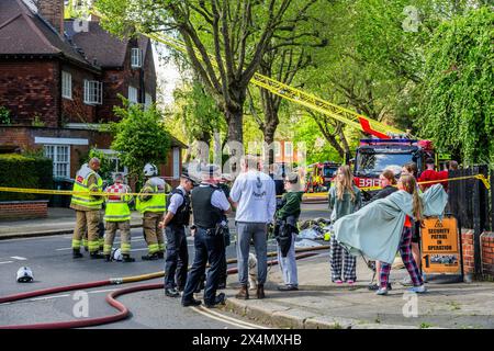 London, Großbritannien. Mai 2024. Viele Feuerwehrfahrzeuge, Krankenwagen und Polizisten nehmen bei einem Brand in einem großen Haus an der Elsworthy Road im Gebiet von Primrose Hill Teil. Das Feuer scheint klein gewesen zu sein und ist aus und die Notfallteams beginnen sich zu zerstreuen, während die vertriebene Familie zusieht. Zehn Feuerwehrfahrzeuge und etwa 70 Feuerwehrleute reagierten. Die Hälfte des zweiten Obergeschosses in einem freistehenden Haus mit drei Stockwerken wurde durch den Brand beschädigt. Eine der 32 m hohen Leiter der Brigade wurde zusammen mit Feuerwehrleuten aus West Hampstead, Paddington, Kentish Town eingesetzt. Credit Guy Bell/Alamy Live News Stockfoto