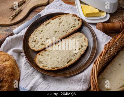 Knusprige Brotscheiben auf einem Teller mit Butter und Weizenohren für ein gemütliches, hausgemachtes Gefühl Stockfoto