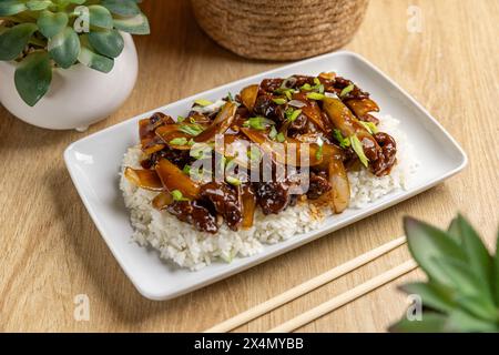 Herzhaftes mongolisches Rindfleischgericht auf Reis mit Essstäbchen Stockfoto