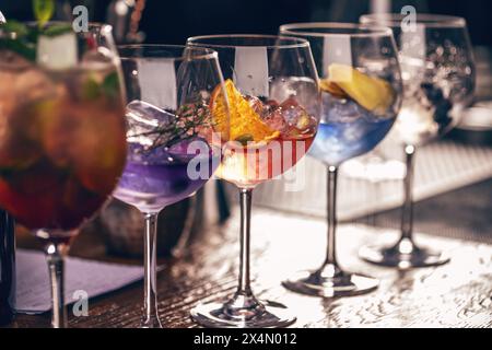 Auswahl an lebhaften, farbenfrohen Craft-Cocktails, serviert in raffiniertem Stielgeschirr an einer Bartheke Stockfoto
