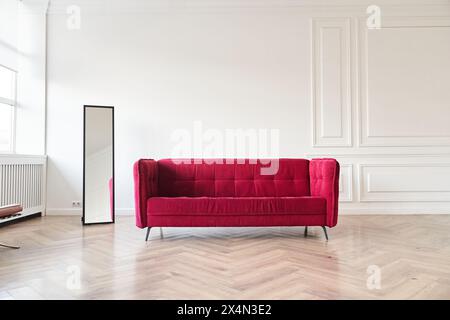 Modernes Innendesign in minimalistischem Stil, im Wohnzimmer mit rotem Sofa, Spiegel und einem Platz, um Ihr Design mit einer leeren Wand für Poster oder Gemälde zu kopieren. Hochwertige Fotos Stockfoto