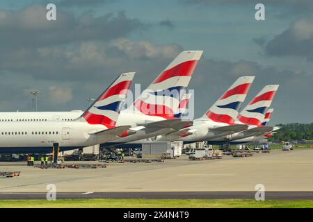 London, England, UK - 4. Mai 2024: Reihe von Heckflossen von Flugzeugen, die von British Airways am Flughafen London Heathrow betrieben werden. Stockfoto