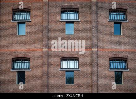 Außenansicht eines ehemaligen Gefängnisgebäudes, Nahaufnahme einer Ziegelmauer und Fenster mit Metallstäben Stockfoto